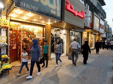 Iraqi people walk past shops in Baghdad, Iraq. (Reuters)
