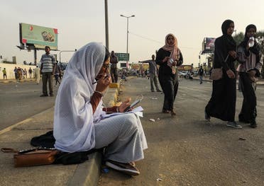 Alaa Salah, a Sudanese woman propelled to internet fame earlier this week after clips went viral of her leading powerful protest chants against President Omar al-Bashir, speaks on the phone as she sits during a demonstration in front of the military headquarters in the capital Khartoum on April 10, 2019. (AFP)