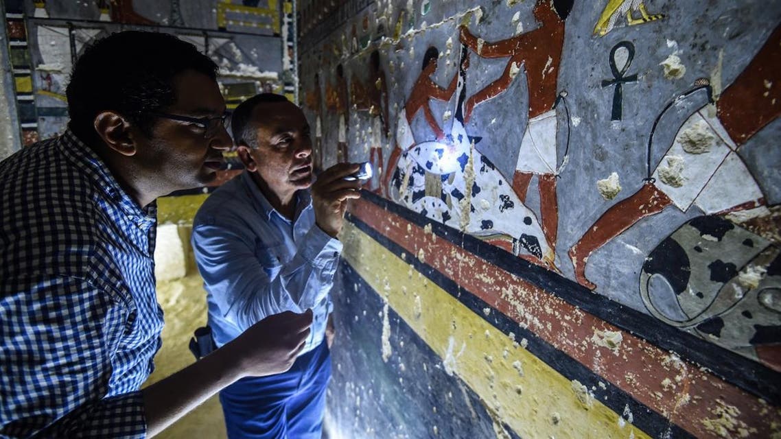 Mohamed Mujahid (L), head of the Egyptian mission which discovered the tomb of the ancient Egyptian nobleman "Khuwy" dating back to the 5th dynasty, inspects the tomb's walls inside at the Saqqara necropolis. (AFP)