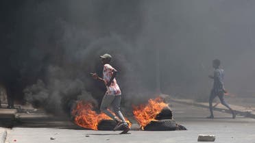 Somali demonstrators run past burning tires during a protest against Somali police in Mogadishu. (Reuters)