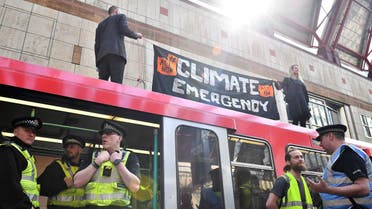 Climate change protestors stand atop a DLR train at Canary Wharf station. (AFP)
