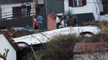 People stand next to the wreckage of a bus after the accident in the Portuguese Island of Madeira on April 17, 2019. (Reuters)