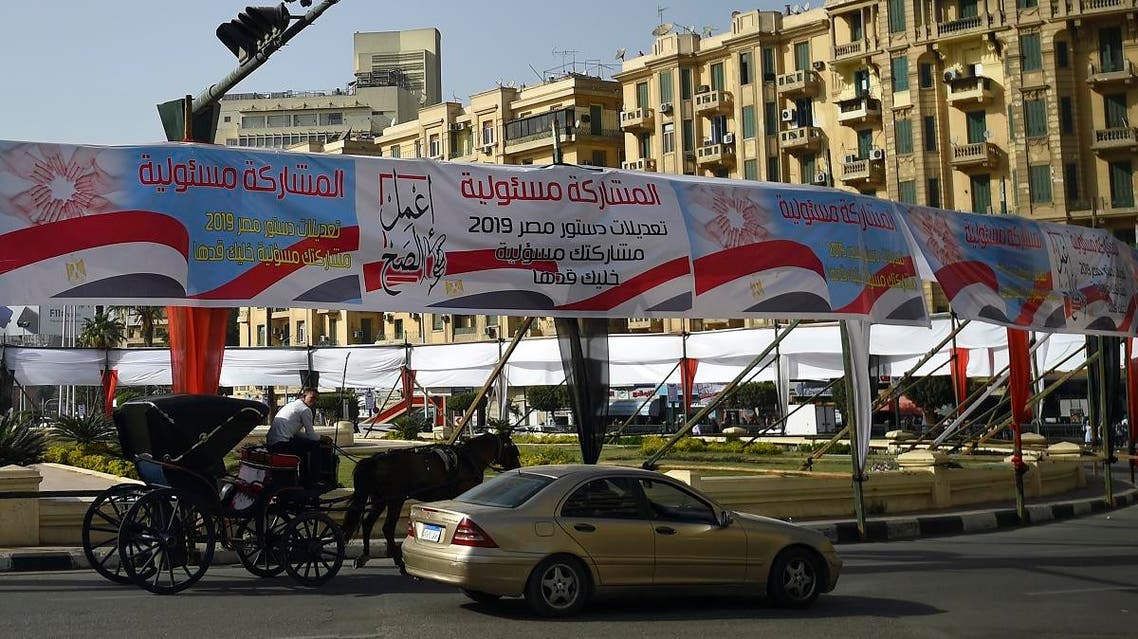 Egyptians pass under banners reading in Arabic “Do what is right”, and “Participation is your responsibility”, urging voters to participate in the upcoming referendum for the constitutional amendments. (AFP)