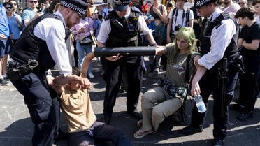 Police officers move climate change activists with their hands glued to a pipe as they continue to block the road at Oxford Circus in London. (AFP)
