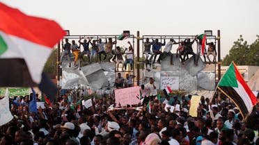 Sudanese protesters wave national flags and shout slogans as they gather for a mass protest in front of the Defence Ministry in Khartoum. (Reuters)