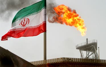 A gas flare on an oil production platform in the Soroush oil fields is seen alongside an Iranian flag in the Persian Gulf, Iran, July 25, 2005. (Reuters)