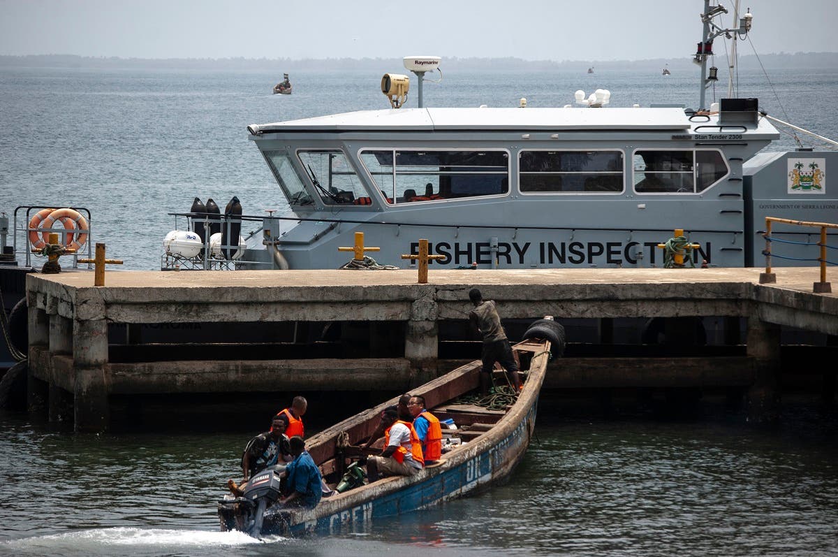 Chinese fishermen in a wooden carved boat are seen at the port in Freetown’s Murray Town suburb on April 8, 2019 with the only Joint Maritime Committee (JMC) offshore patrol boat, donated by the World Bank, in the background. (AFP)