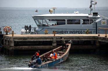 Chinese fishermen in a wooden carved boat are seen at the port in Freetown’s Murray Town suburb on April 8, 2019 with the only Joint Maritime Committee (JMC) offshore patrol boat, donated by the World Bank, in the background. (AFP)