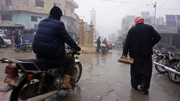 A Syrian man rides his motorcycle past a pedestrian in the village of Kafranbel in the northwestern province of Idlib. (AFP)