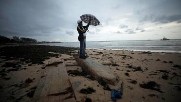 A man holds an umbrella beneath storm clouds over Wimbe beach in Pemba. (Reuters)
