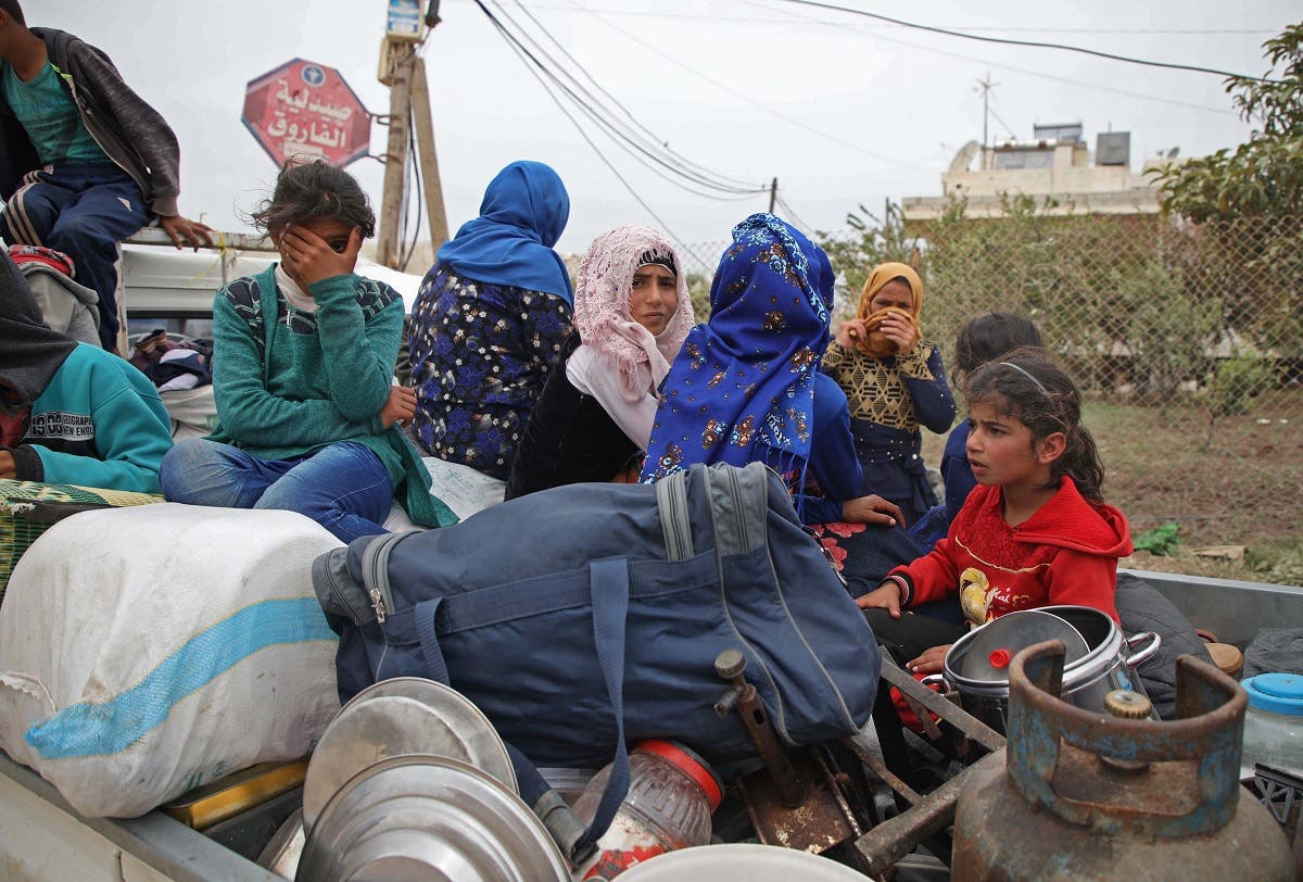 A Syrian family, riding in the back of a truck loaded with belongings, flee from reported regime shelling on Hama and Idlib provinces on May 1, 2019. (AFP)