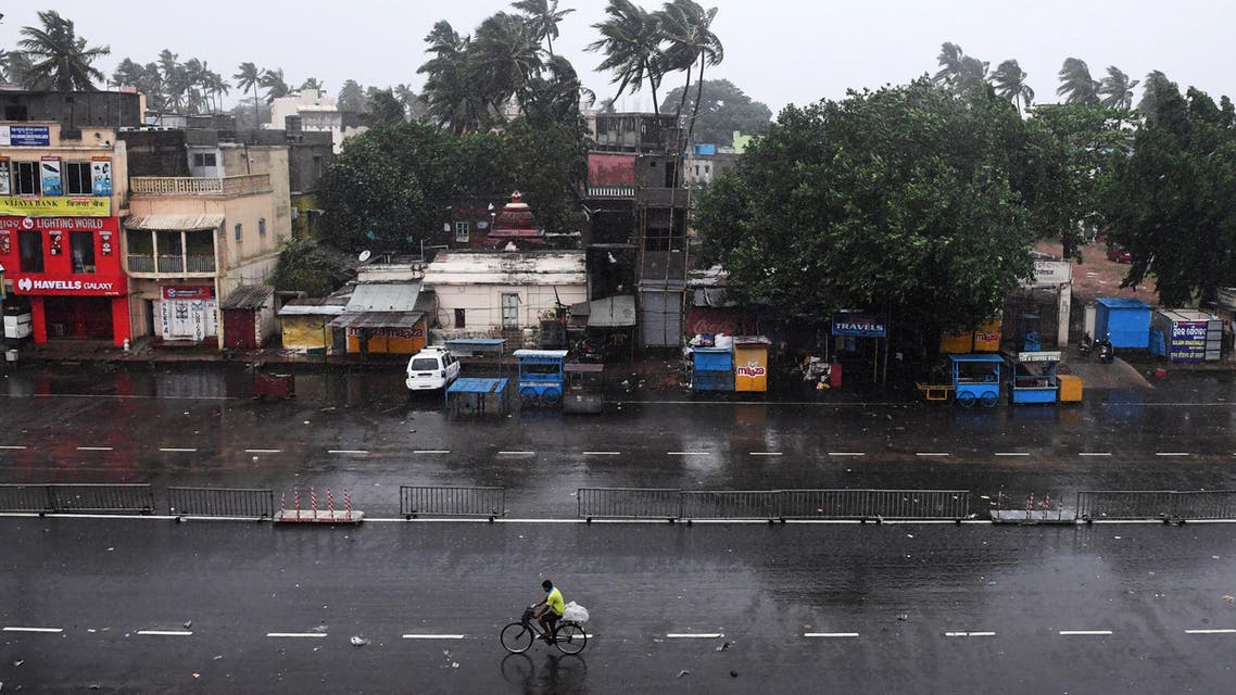 A lone Indian commuter (C) cycles down nearly deserted road in Puri in the eastern Indian state of Odisha early on May 3, 2019, as Cyclone Fani approaches the Indian coastline. (AFP)