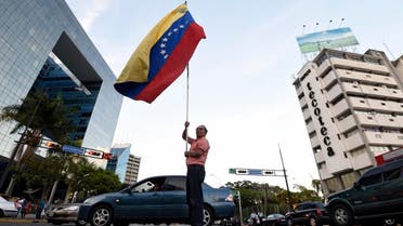 An anti-government demonstrator waves a Venezuelan national flag in the middle of the street in front of the Parque Cristal building. afp