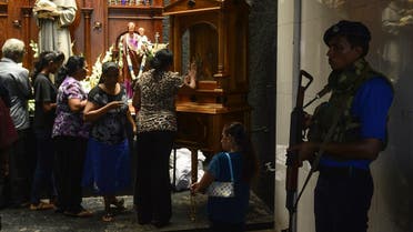 A Sri Lankan Navy personnel stands guard as Catholic devotees pray at St. Anthony's church on May 7, 2019. (AFP)