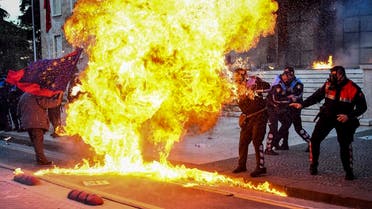 Albanian policemen try to avoid the flames from a petrol bomb during an anti-government protest called by the opposition. (AFP)