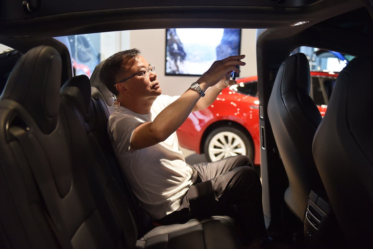 A man takes a photo inside a Tesla Model X in a Tesla showroom in Beijing. (AFP)