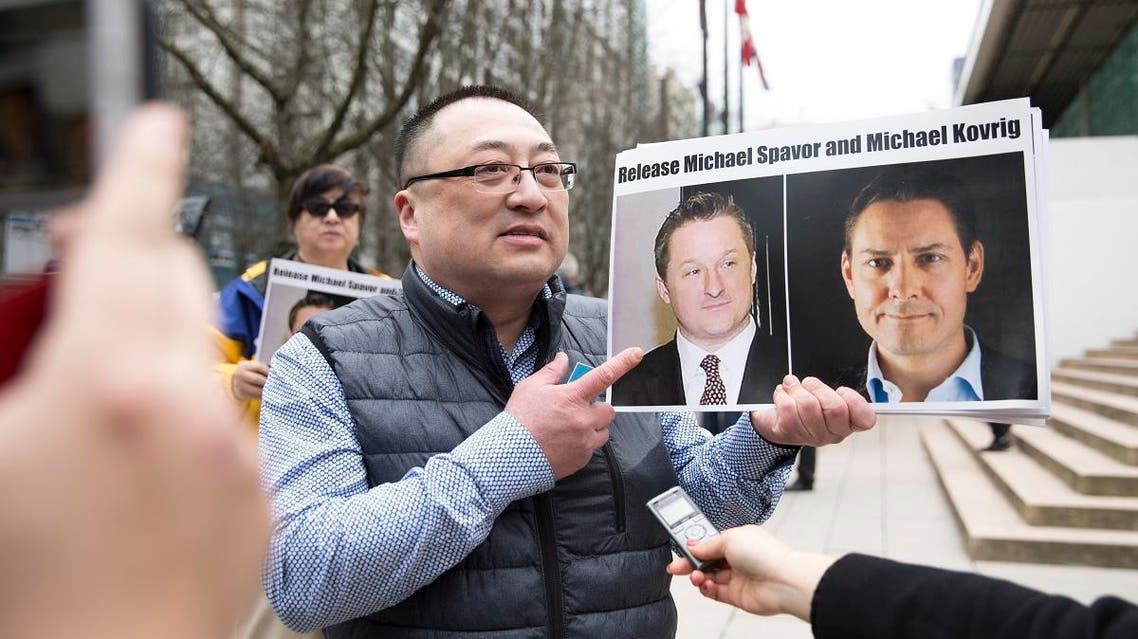 Louis Huang of Vancouver Freedom and Democracy for China holding photos of Canadians Michael Spavor and Michael Kovrig, who are being detained by China, outside British Columbia Supreme Court, in Vancouver. (AFP)