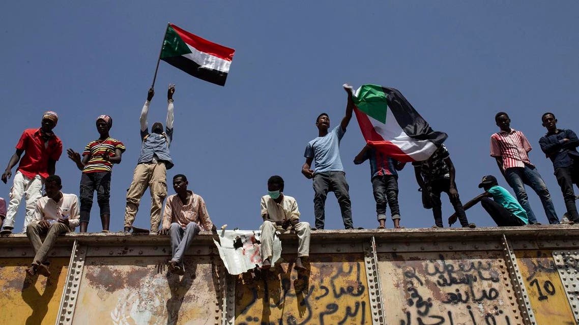 Sudanese protesters wave national flags at the sit-in outside the military headquarters, in Khartoum. (AP)