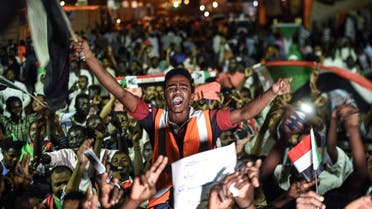 Sudanese protesters wave flags and flash victory signs as they gather for a sit-in outside the military headquarters in Khartoum. (AFP)