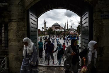 People enter to Sultanahmet (Blue) mosque on August 22, 2017 near the Hagia Sophia (in the background) during a rainy day in Istanbul. (AFP)