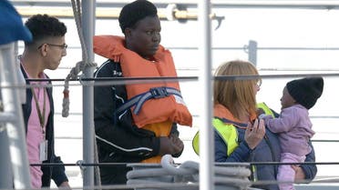 A woman (C) and a child (R) with the migrants who were stuck on a ship since their rescue in the Mediterranean 10 days ago, are being welcomed after disembarking in Valletta, Malta, on April 13, 2019 after four European countries agreed to take the migrants in. (AFP)