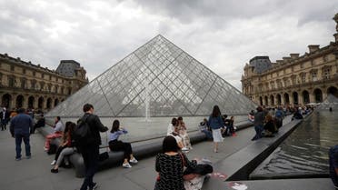 Tourists walk around the pyramide of the Louvre museum, in Paris, May 17, 2019. (AP)