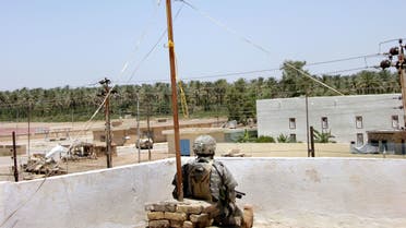 A US soldiers takes a break under an Iraqi flag on the roof on newly reconstructed police station in the Iraqi town of Tarmiyah, north of Baghdad, 25 May 2006. In the aftermath of the US-led invasion, Tarmiyah became known for little more than deadly roadside bombs and conservative Sunni sermons in its mosques. But now the largely Sunni town of 45,000 people, nestled amid endless date palms plantations on the edge of the Tigris just north of Baghdad, is being held up by the US military as a model in its efforts to secure and rebuild Iraq. AFP PHOTO/HO/US ARMY/SGT. TREVOR SNYDER