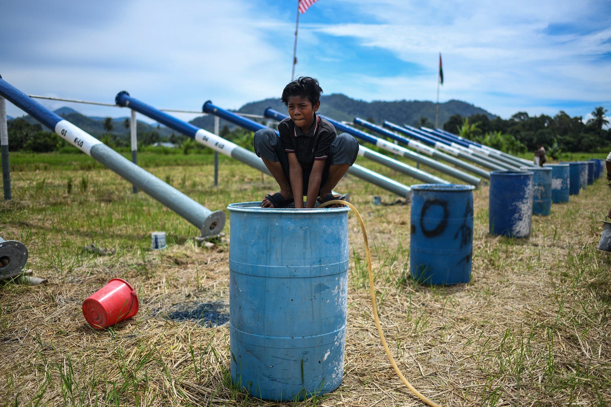 A boy filling water in a drum before firing steel cannons on the eve of Eid al-Fitr in Kuala Kangsar on June 4, 2019. (AFP)