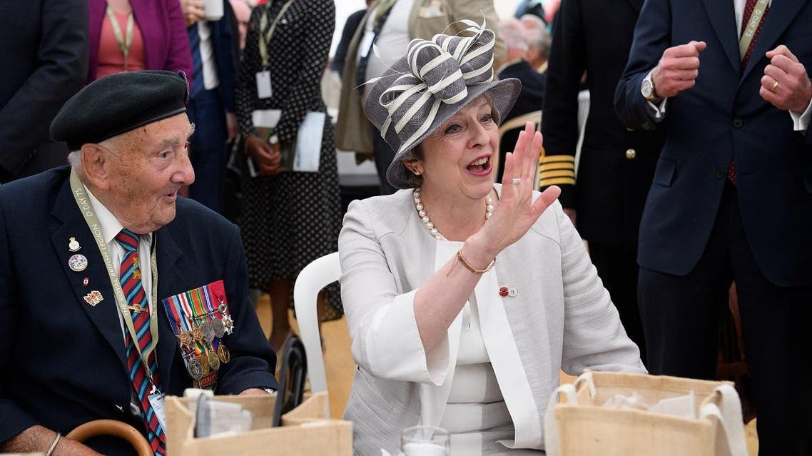British Prime Minister Theresa May (R) waves to another man as she chats with veteran Leslie Stocking (L), following a service of remembrance at Bayeux cemetery in Bayeux, France, on June 6, 2019. (Reuters)