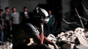A member of the Syrian Civil Defence reacts as others clear debris while searching for bodies or survivors in a collapsed building following a reported government air strike in the village of Saraqib in Syria's northwestern Idlib province. (AFP)