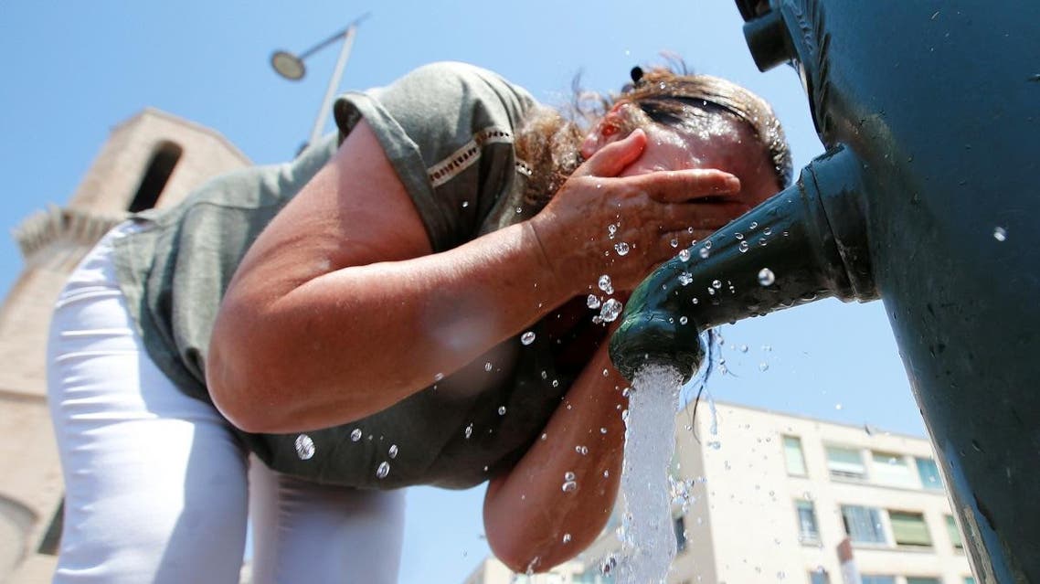 A woman cools off in a water fountain in Marseille as a heatwave hits much of the country. (Reuters)