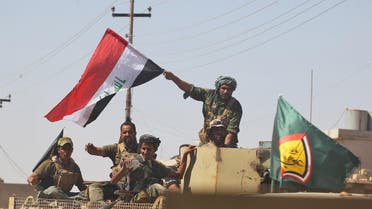 A fighter of Hashed Al-Shaabi (Popular Mobilization militias) waves an Iraqi flag as others use a cell phone to take a selfie from the turret of an armored vehicle during the advance in the town of Tal Afar, west of Mosul. (File photo: AFP)