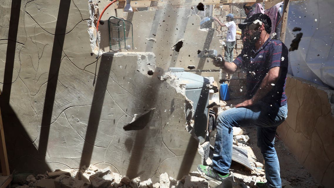 In this Sunday, June 16, 2019 photo, a Syrian refugee demolishes a concrete wall built inside his tent at a refugee camp in the eastern Lebanese border town of Arsal, Lebanon. Lebanon's state-run National News Agency said Monday, July 1, 2019 that Lebanese troops have entered refugee settlements in a town near the Syrian border to make sure that brick and concrete walls have been torn down. Arsal is home to 60,000 refugees who live in informal camps set up in the fields. (AP Photo/Bilal Hussein)