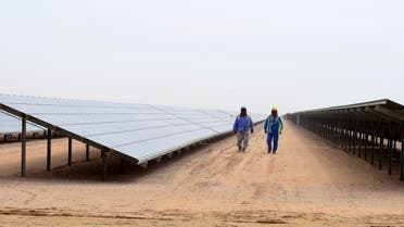 Employees walk past solar panels at the Mohammed bin Rashid Al-Maktoum Solar Park on March 20, 2017, in Dubai. Dubai completed a solar plant big enough to power 50,000 homes as part of a plan to generate three-quarters of its energy from renewables by 2050. (AFP)