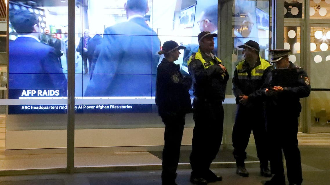 police officers stand in front of a television screen at the main entrance to the Australian Broadcasting Corp. building in Sydney. (AP)