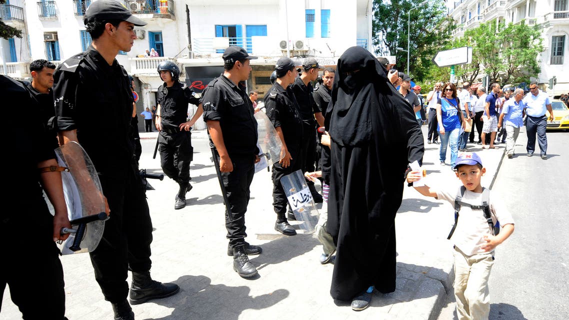 A Tunisian woman, wearing a niqab, walks in front of police officers after Friday prayers, on June 15, 2012 in Tunis. Public security in Tunisia was normal throughout the country ahead of Friday prayers, after which several religious groups had planned protest rallies, an interior ministry spokesman said. At the last minute on June 14, fundamentalist Islamic groups and the moderate Muslim Ennahda party in power called off the rallies they had planned to hold following Friday prayers, after the government issued a ban. AFP PHOTO / FETHI BELAID