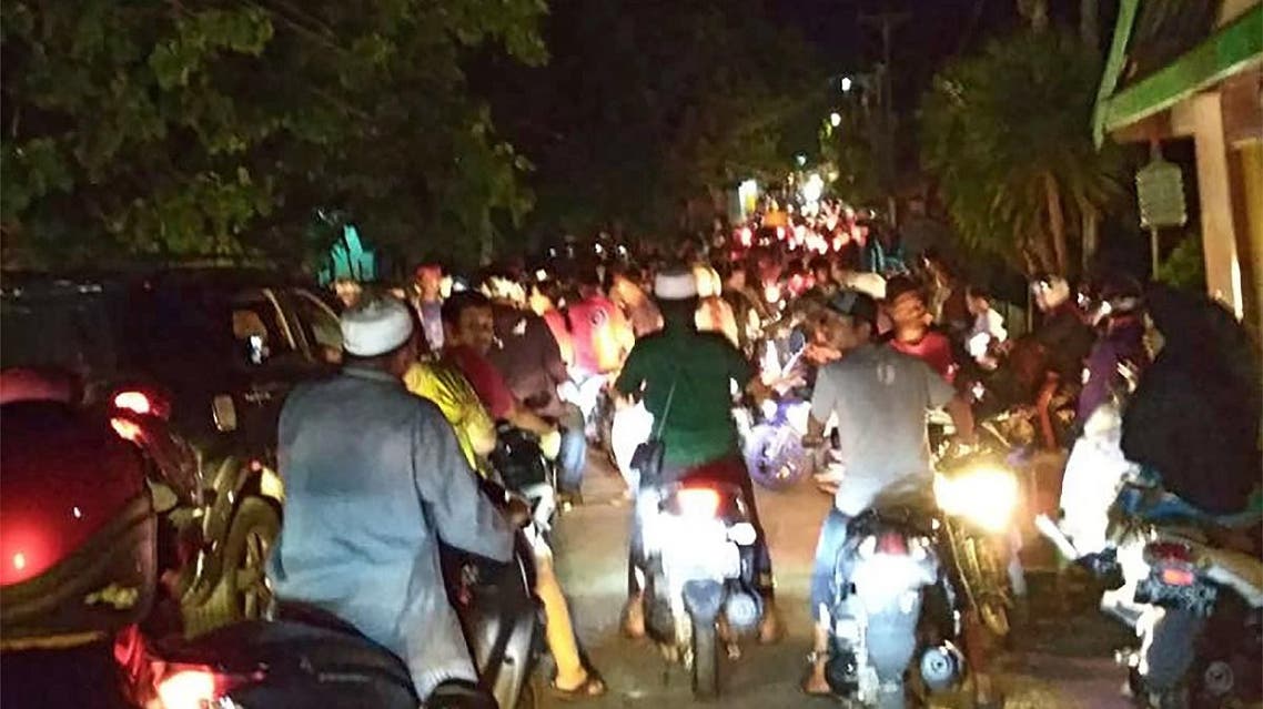 This photograph taken with a phone shows Indonesian residents rushing for higher ground fearing a tsunami after a strong earthquake rocked Luwuk, in Central Sulawesi of eastern Indonesia on April 12, 2019. (AFP)