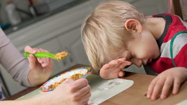 Blond boy holds hand on his mouth to stop eating - Stock image