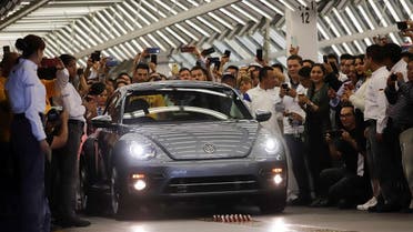 Employees take pictures of a Volkswagen Beetle car during a ceremony marking the end of production of VW Beetle cars. (Reuters)