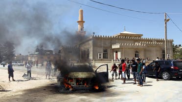 Benghazi residents and Libyan security forces gather around a burning car after an explosion killed the military prosecutor for Western Libya Youssef Ali al-Asseifar on August 29, 2013. (AFP)