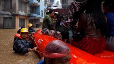 A woman carrying a child is moved by rescue workers towards dry ground from a flooded colony in Kathmandu, Nepal, on July 12, 2019. (Reuters)