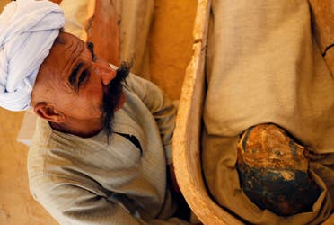 A man sits next to a mummy that was discovered near the King Amenemhat II pyramid, south of Cairo. (Reuters)