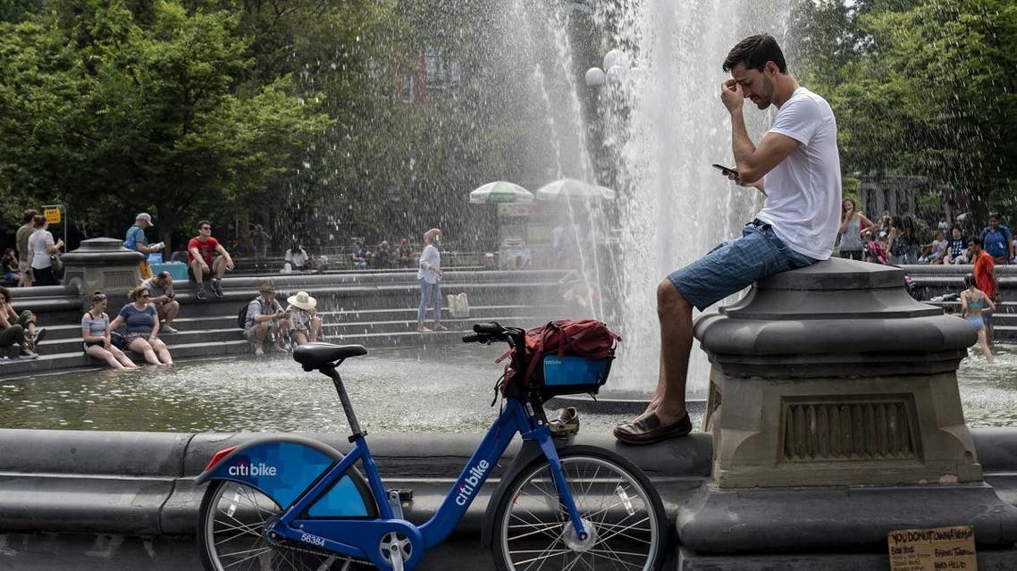 People cool off near the fountain at Washington Square Park during a hot afternoon day. (AFP)