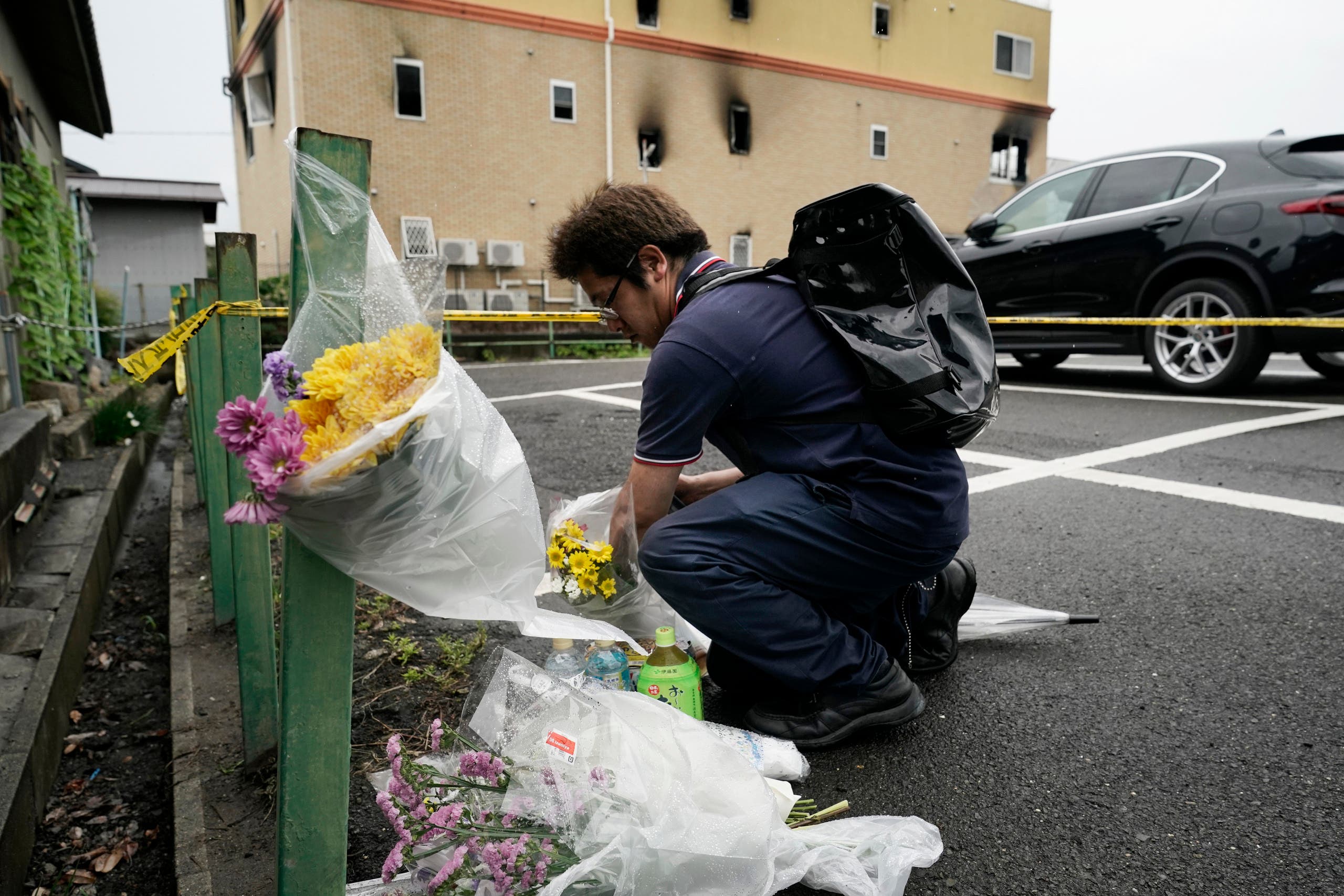 A man places flowers outside the Kyoto Animation Studio building consumed in an arson attack in Kyoto, Japan. (AP)