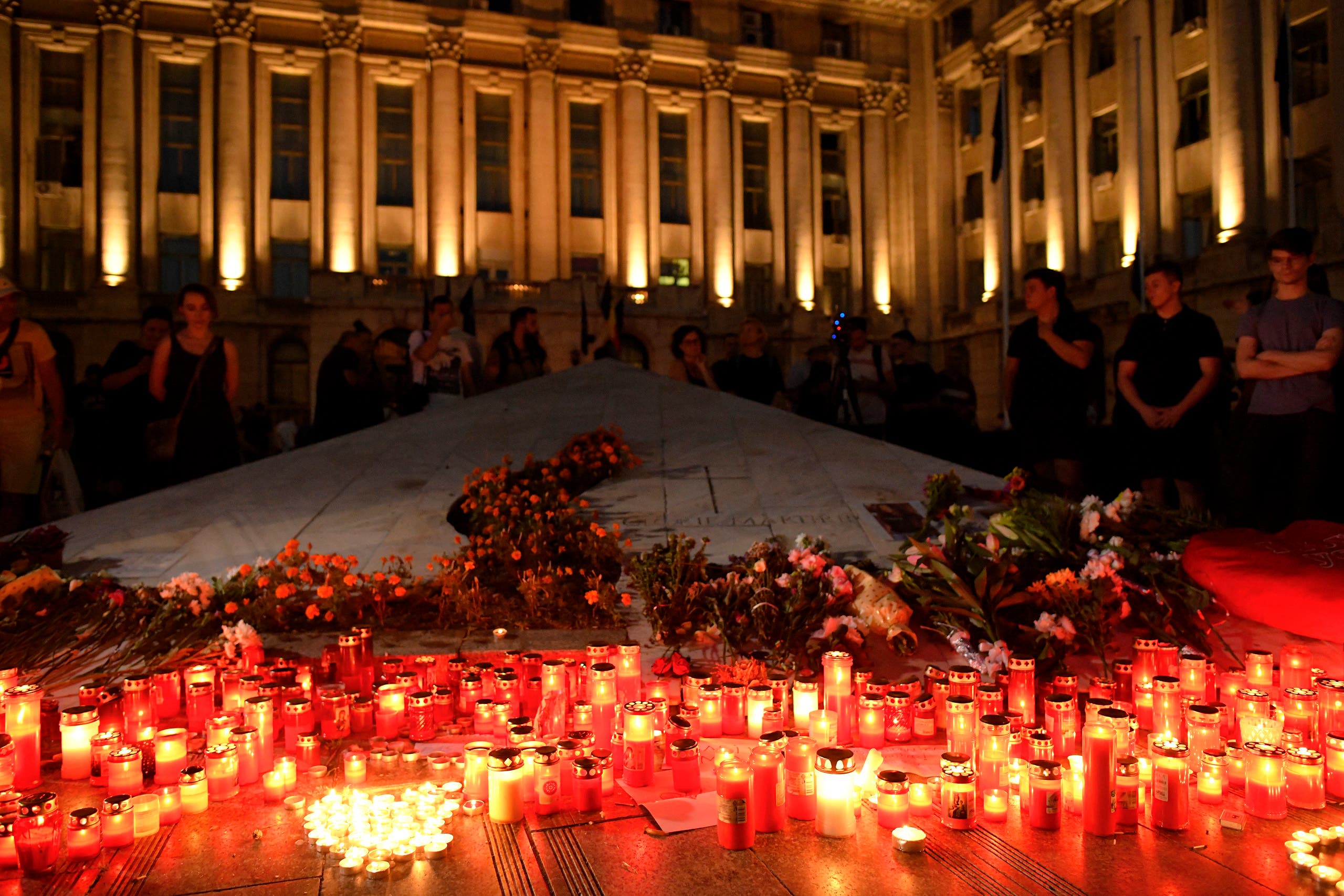 Candles are lit outside the interior ministry building in memory of a 15-year-old girl, raped and killed in southern Romania, after police took 19 hours from the moment she called the country's emergency hotline to intervene. (AP)