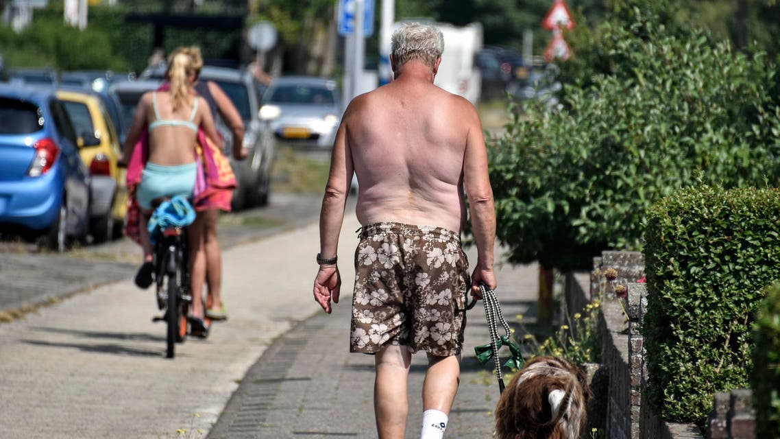 A man and his dog walk without a shirt in the summer heat on Thursday, July 25, 2019 in the city of Egmond, northern Netherlands. (AP)