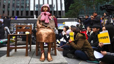 South Korean protesters sit near a statue of a teenage girl symbolizing former "comfort women", who served as sex slaves for Japanese soldiers during World War II, during a weekly anti-Japanese demonstration in front of the Japanese embassy in Seoul on November 21, 2018. (AFP)