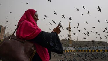 A Muslim pilgrim snaps pictures of pigeons as she walks in the streets of the Saudi holy city of Mecca. (AFP)