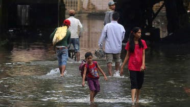 People walk past a waterlogged street after rainfall in Mumbai, India, Wednesday, July 24, 2019. (AP)