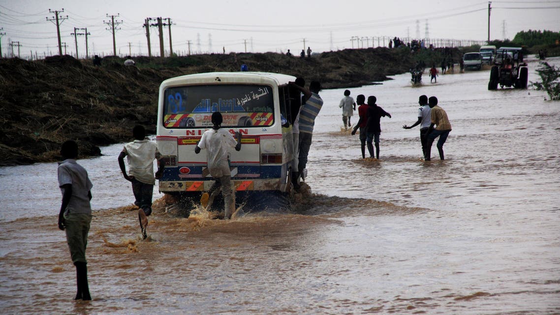 Sudanese men run in flood water to catch a bus in Khartoum, Sudan. (File photo: AP)